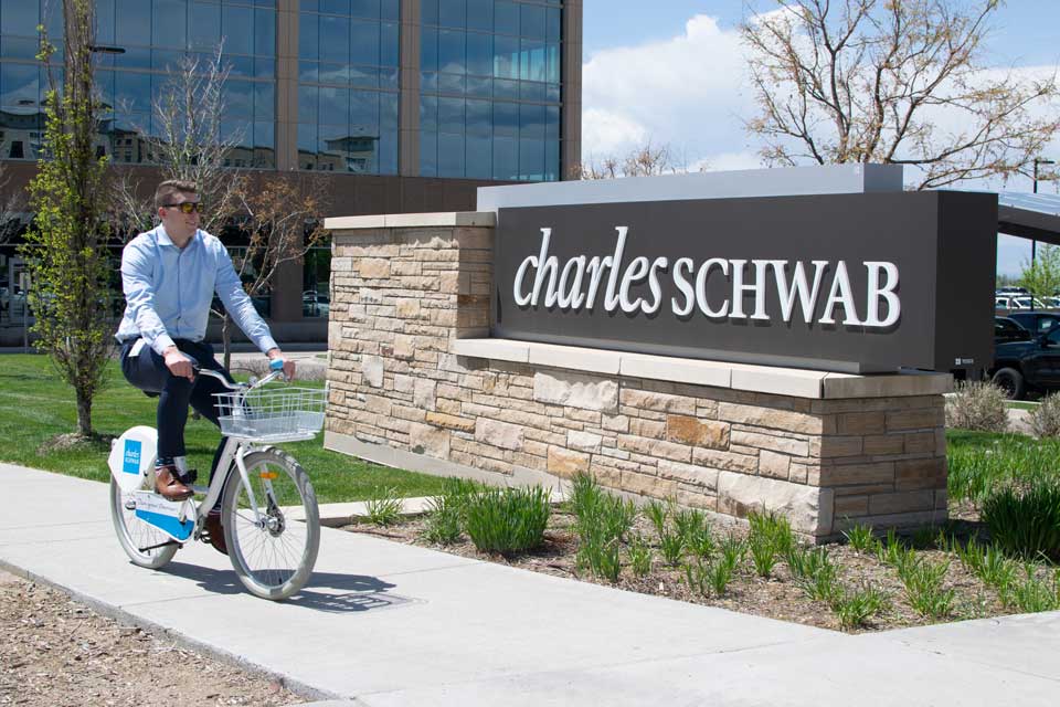 Man riding his bike in front of the Charles Schwab sign.
