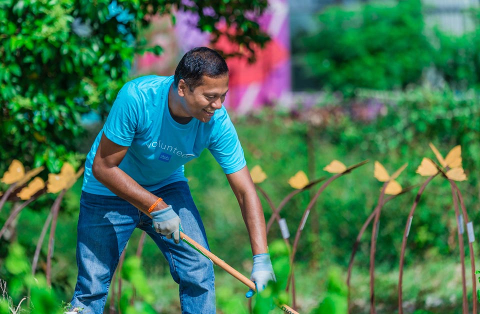 Schwab volunteer raking a garden.