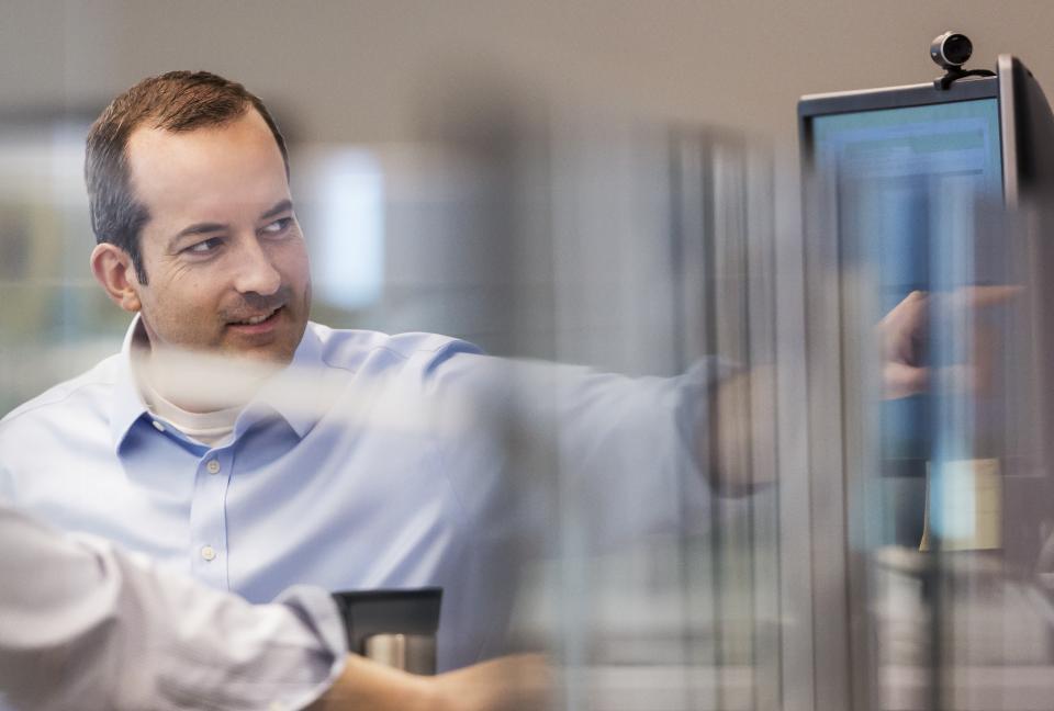 Man showing a colleague something on the screen.